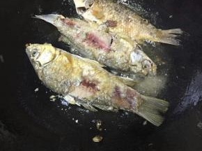 热锅倒油，油开后转小火，将处理好的鲫鱼慢慢滑入锅中煎炸，炸至表皮金黄即可