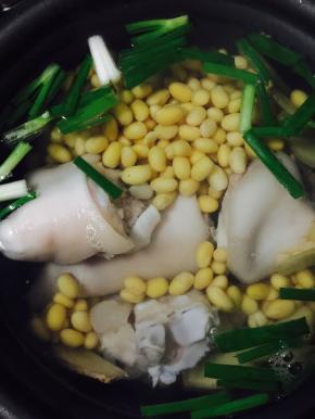 把猪蹄放入电饭锅中，加黄豆、姜片、葱和盐，按下煲汤模式（没有的按下煮饭模式）