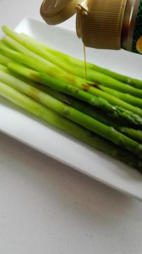 捞出的芦笋在盘子上摆放整齐，淋上生抽和芝麻