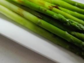 捞出的芦笋在盘子上摆放整齐，淋上生抽和芝麻