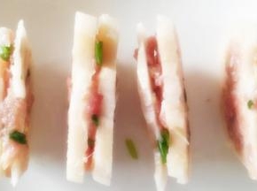 把准备好的肉馅用拇指捏进藕片里面，放入盘中。