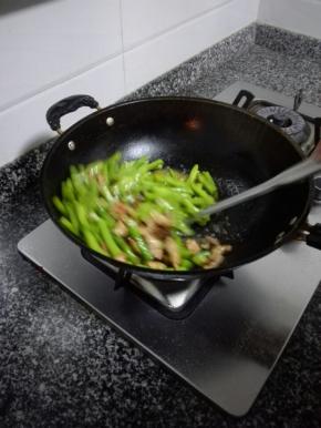 热油爆炒四季豆，煸炒至变色软熟后加入肉片