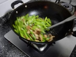 热油爆炒四季豆，煸炒至变色软熟后加入肉片
