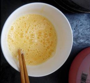 在碗中加入少许食盐，葱花，用筷子搅拌，至蛋液气泡