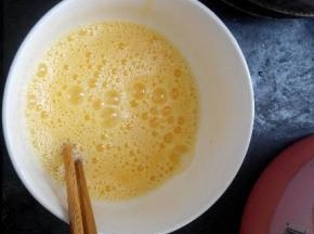 在碗中加入少许食盐，葱花，用筷子搅拌，至蛋液气泡