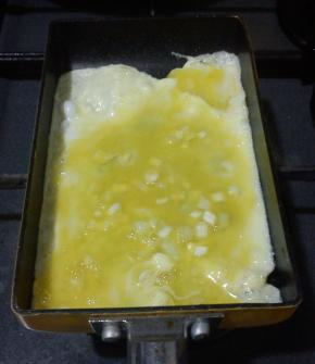 倒入少许的蛋液，晃动煎锅，使其均匀的铺满，小火慢煎，有起泡的地方用筷子戳破