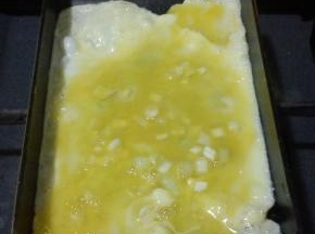 倒入少许的蛋液，晃动煎锅，使其均匀的铺满，小火慢煎，有起泡的地方用筷子戳破