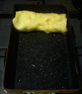 蛋液渐渐凝固之后，用筷子挑起一端，向另一端慢慢卷起