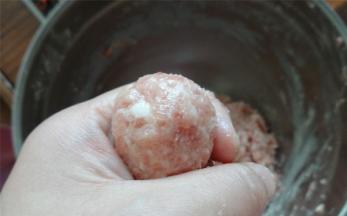 将肉馅放在手中，由虎口处挤压形成肉丸