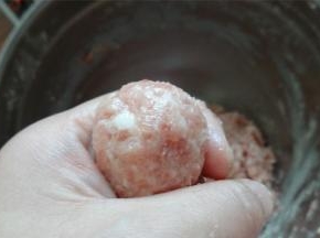 将肉馅放在手中，由虎口处挤压形成肉丸