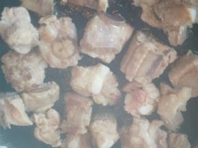 捞出排骨，沥干，炒锅中加入少许油加热，放入排骨，煎至双面金黄