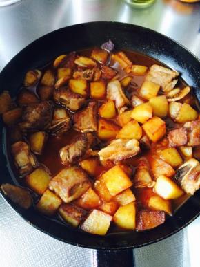 将煎好的排骨放入锅中，与土豆一起翻炒，放入生抽，料酒，白糖调味。加入开水烧至沸腾