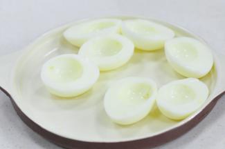 将4个鸡蛋放入水中煮熟，然后剥壳，用刀切成两半，将鸡蛋黄挖掉