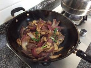 洋葱8成熟后倒入之前炒好的肉片混炒，加盐调味，撒上葱段出锅