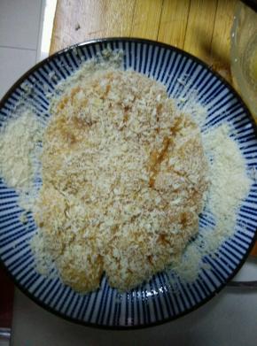 盘中放入适量的面包糠，把腌制好的鸡胸肉放入，使其包裹上一层厚厚的面包糠