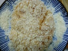 盘中放入适量的面包糠，把腌制好的鸡胸肉放入，使其包裹上一层厚厚的面包糠