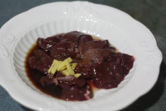 在熬粥的同时，将猪肝洗净切片，用盐、料酒、油、玉米淀粉和姜丝腌制片刻