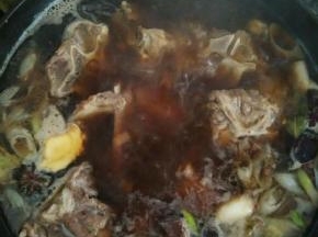 炒出香味加入开水淹没食材，放入香叶，草果和冰糖