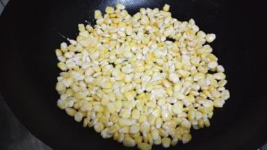 炒锅小火放少量的油加热，倒入玉米粒，用铲子压平成一个圆
