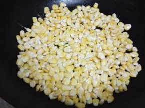 炒锅小火放少量的油加热，倒入玉米粒，用铲子压平成一个圆