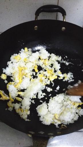 鸡蛋快要凝固的时候将米饭倒入，用铲子将米饭压扁