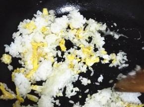 鸡蛋快要凝固的时候将米饭倒入，用铲子将米饭压扁