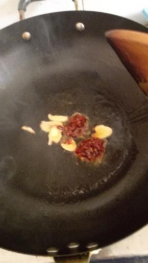 锅内放油烧热，加入姜蒜和豆瓣酱炒出香味