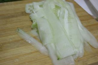 黄瓜洗净用削皮器削成片状，卷成卷放入盘子中