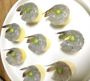 将腌好的虾仁放在豆腐上，中间用一颗豌豆点缀