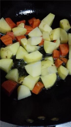 锅内放比炒菜多一点的油，油热之后放入胡萝卜和土豆翻炒至表面金黄，捞出备用