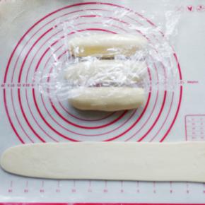 取其中的一份继续搓成细长条，然后用手压平，再用擀面杖擀薄擀长成面片