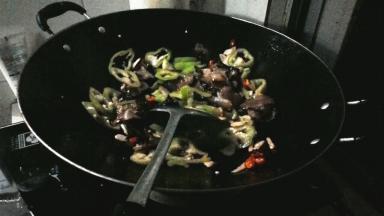 热锅倒油，油烧开后放小米辣和蒜瓣爆香，加腊肉炒出油，炒制2分钟后加青椒翻炒