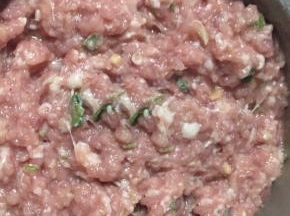 切好的葱姜放入猪肉馅中，加适量的盐搅拌均匀