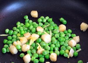 炒锅中放油，油热后倒入腌好的鲜贝，大火快炒；加入半汤匙料酒炒匀，待到鲜贝肉由透明转为白色，立即倒入焯烫过的豌豆粒