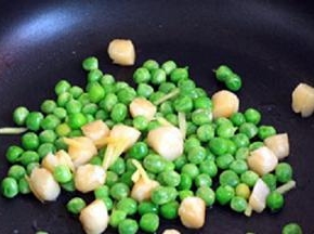 炒锅中放油，油热后倒入腌好的鲜贝，大火快炒；加入半汤匙料酒炒匀，待到鲜贝肉由透明转为白色，立即倒入焯烫过的豌豆粒