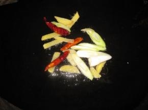 锅中热油，转中小火把干辣椒、生姜、花椒、青椒放入锅中炒香