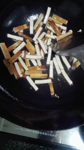 油锅烧热，放上姜蒜粒爆香，倒入豆腐干翻炒