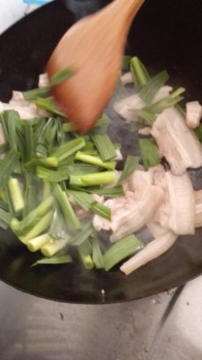 翻炒到肉逐渐变色，微微卷曲加入蒜苗翻炒