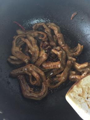 放入鸭掌翻炒，放入白糖，生抽老抽和料酒，给鸭掌上色