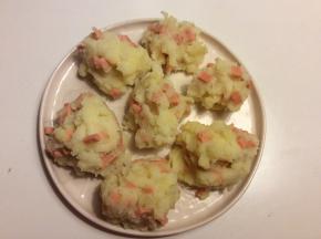 把火腿肠丁混合入土豆泥中搅拌均匀，用手捏成丸子，放在盘子中