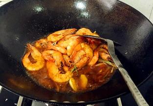 放入调好的料汁，将大虾放入翻炒均匀，倒入适量的料酒，盖上锅盖，大火收汁