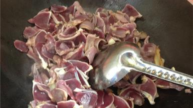 将腌好的鸭胗放入锅内，加一小勺料酒翻炒均匀