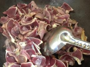 将腌好的鸭胗放入锅内，加一小勺料酒翻炒均匀