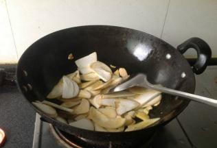 将鸡腿菇倒入油锅中，中小火翻炒