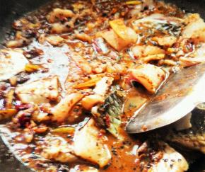 底料炒好后，将腌制的鱼片放入小火翻炒，注意不要将鱼片炒散了