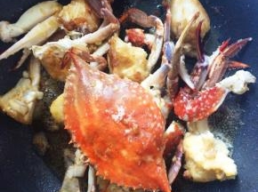 炒锅放油加热，放入腌好的梭子蟹，翻炒至变色捞出