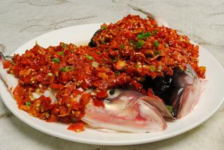 在腌好的鱼头上摆上切好的姜丝，表面再铺上一层红剁椒