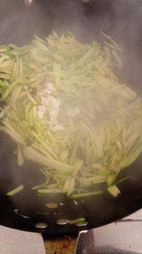 放入蒜末和花椒粒翻炒，炒至南瓜丝变软