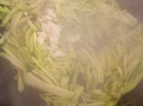 放入蒜末和花椒粒翻炒，炒至南瓜丝变软