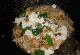 姜片油锅爆香，放上茶树菇，再放入青椒和豆腐一起拌炒